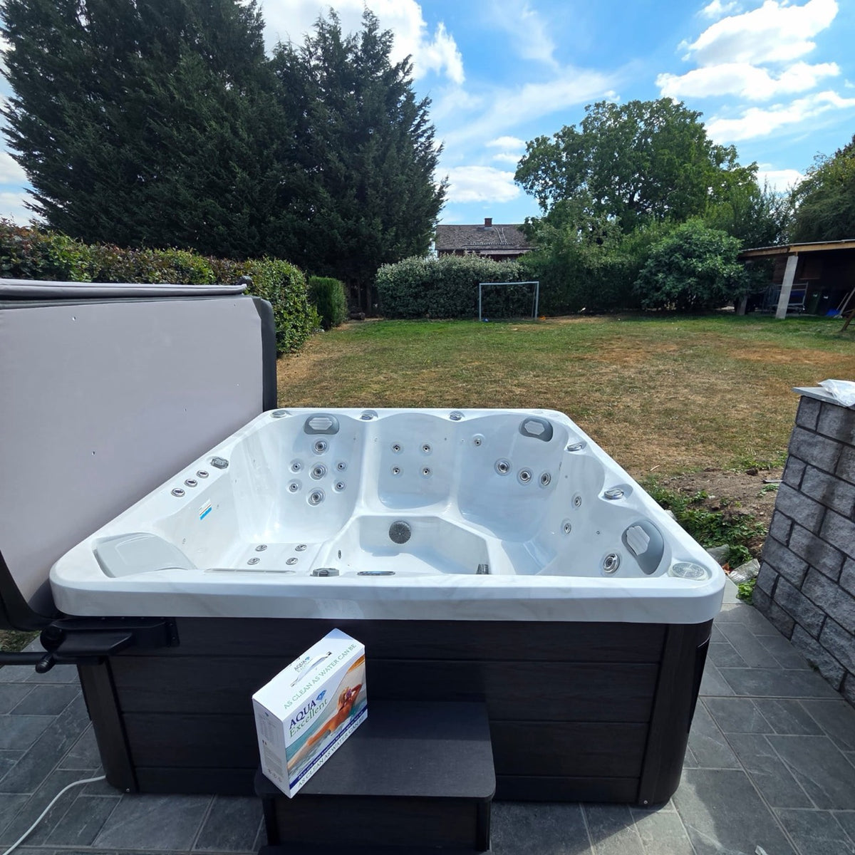Spa blanc et sa couverture devant un jardin arboré